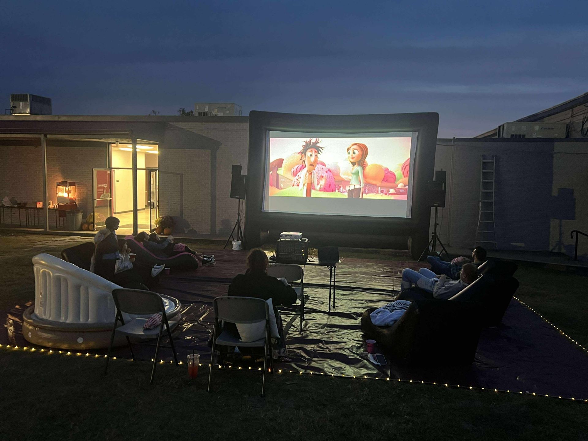 Large inflatable screen sitting on tarp.In fact yards with a movie being watched on it